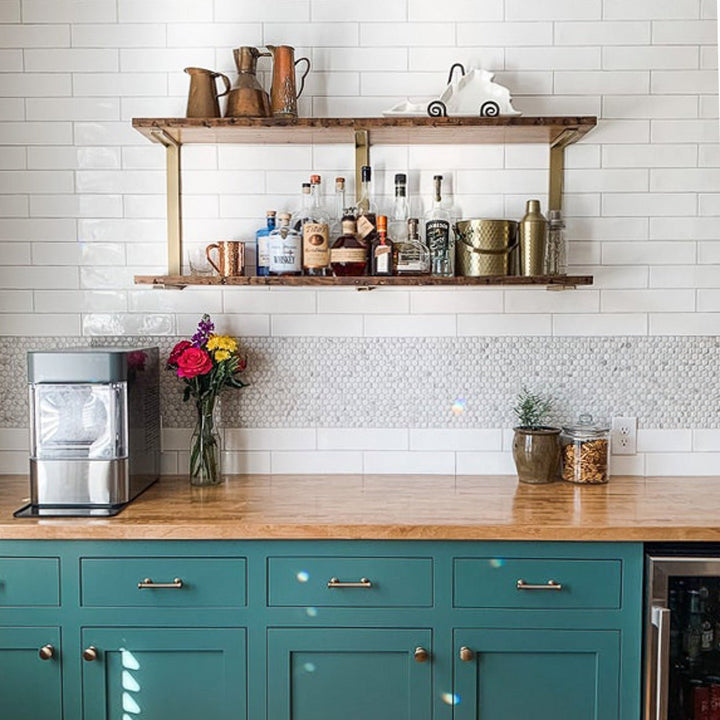 wall mounted shelving unit. Bar shelves above green cainbets and wood couterop. Kitchen with white tile wall and brass shelf brackets