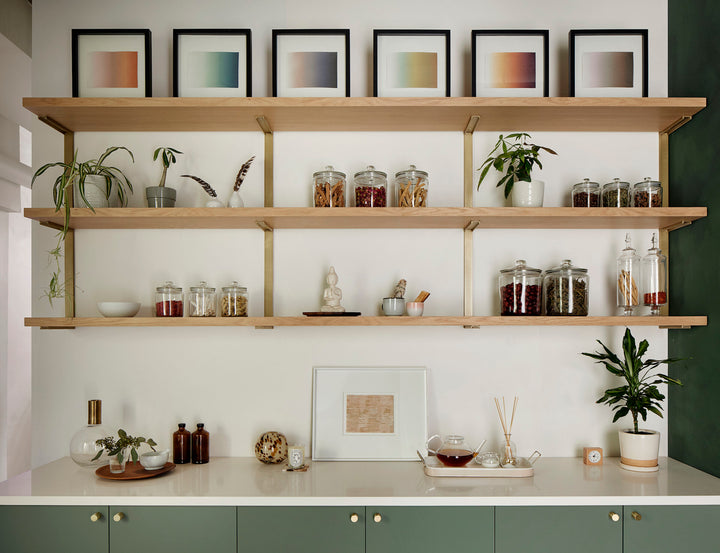 Heavy duty solid steel shelf brackets with brass powder coat finish. Three floating shelves above sage cabinetry and green wall. Apothecary storage shelves by Vault Furniture