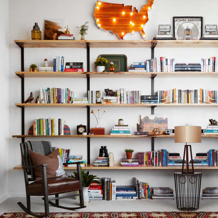 Handcrafted wall-mounted wood and steel bookshelf with eclectic decor, books, and USA wall light—modern industrial shelving unit made in the USA, perfect for stylish home or office organization.