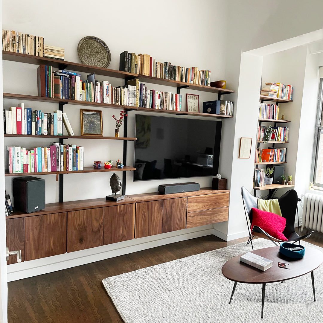 custom wall mounted shelving with cabinetry. solid black walnut shelving system in living room.