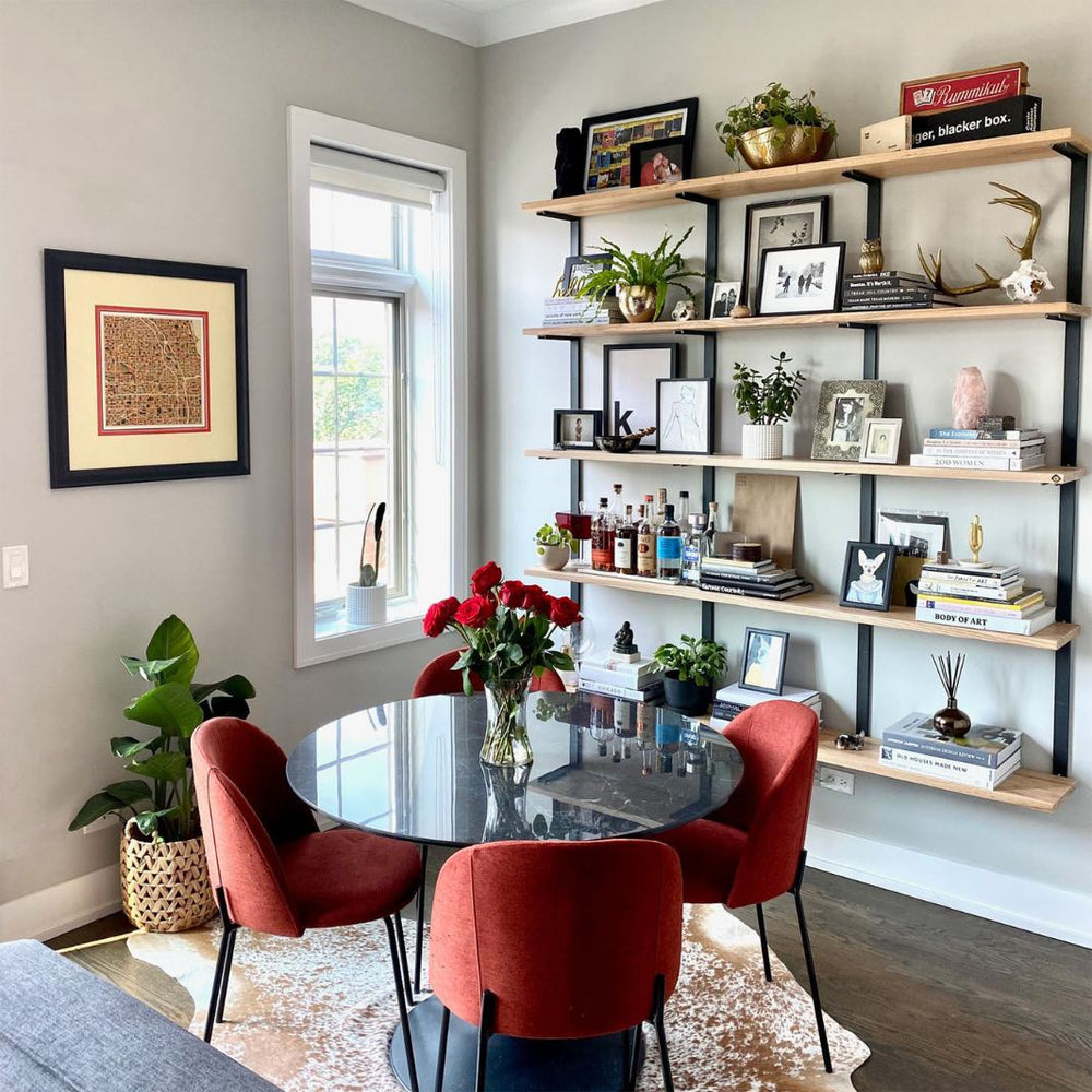 Modern mid century modern living room with wall mounted bookshelf. solid ash wood floating shelves and black steel brackets for a large heavy-duty shelving and storage unit.