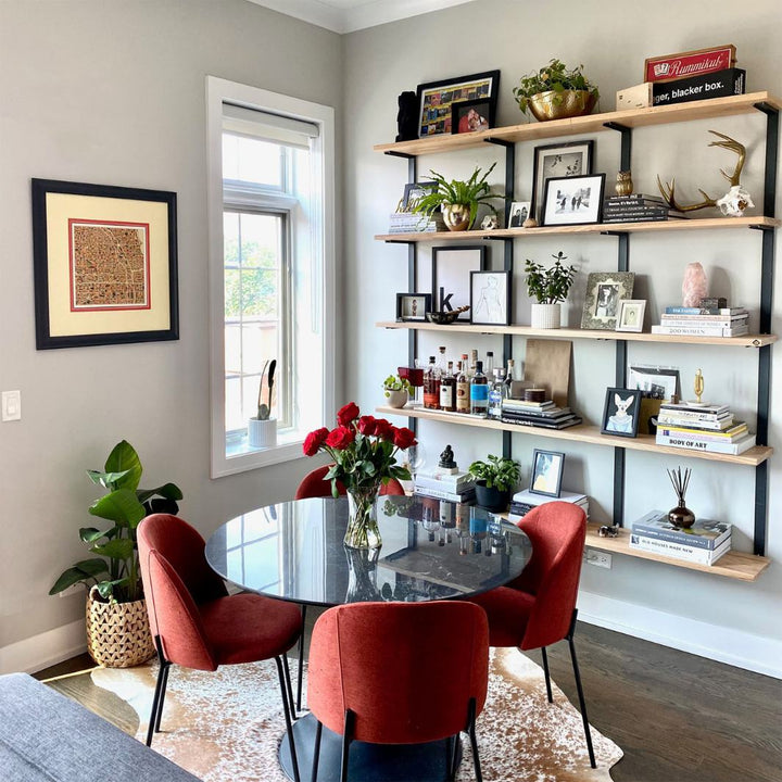 Modern mid century modern living room with wall mounted bookshelf. solid ash wood floating shelves and black steel brackets for a large heavy-duty shelving and storage unit.
