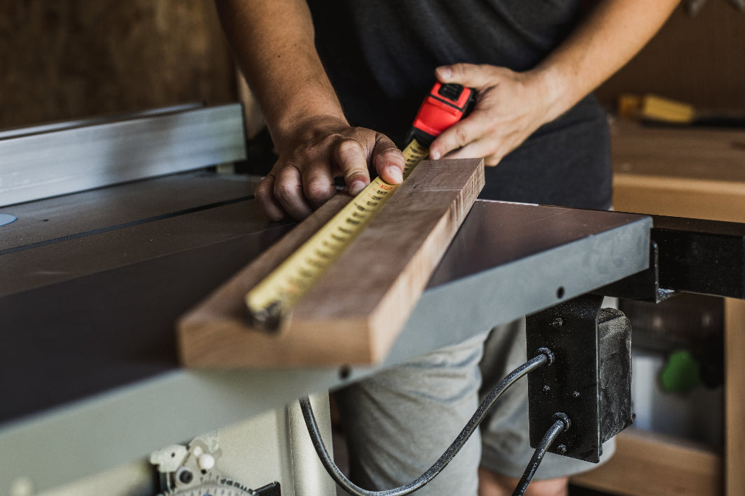 man measures solid wood for furniture building on table saw. 