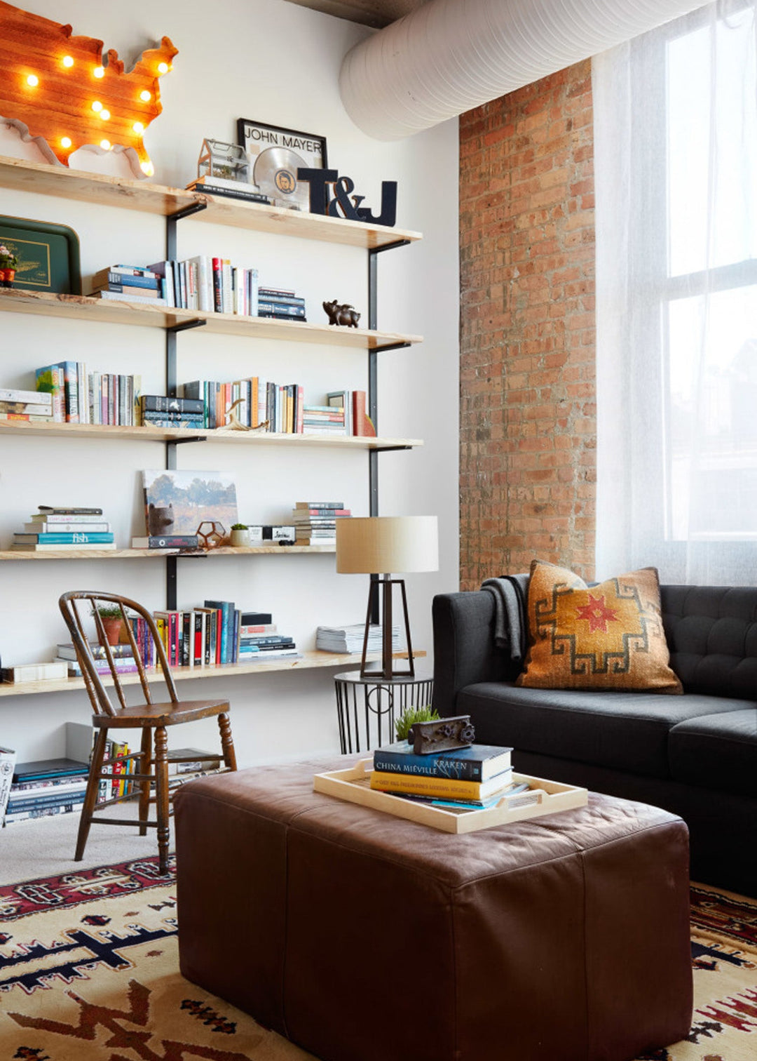 Modern living room with bookshelf, sofa, and ottoman.