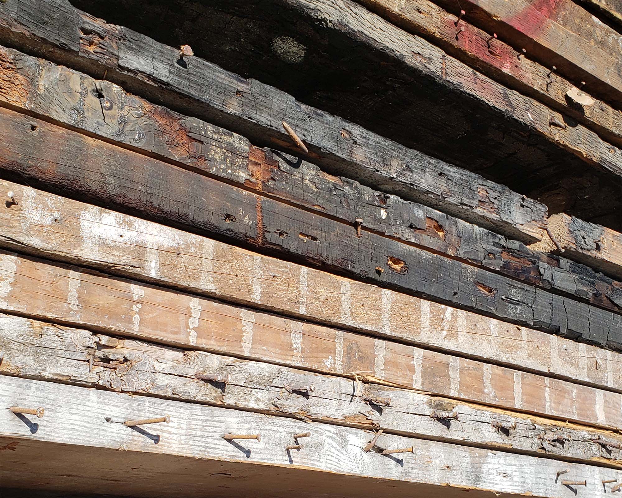 reclaimed barn wood or shelves. stack of reclaimed wood with old nails, burnt wood and plaster wall lines. Vault furniture materials